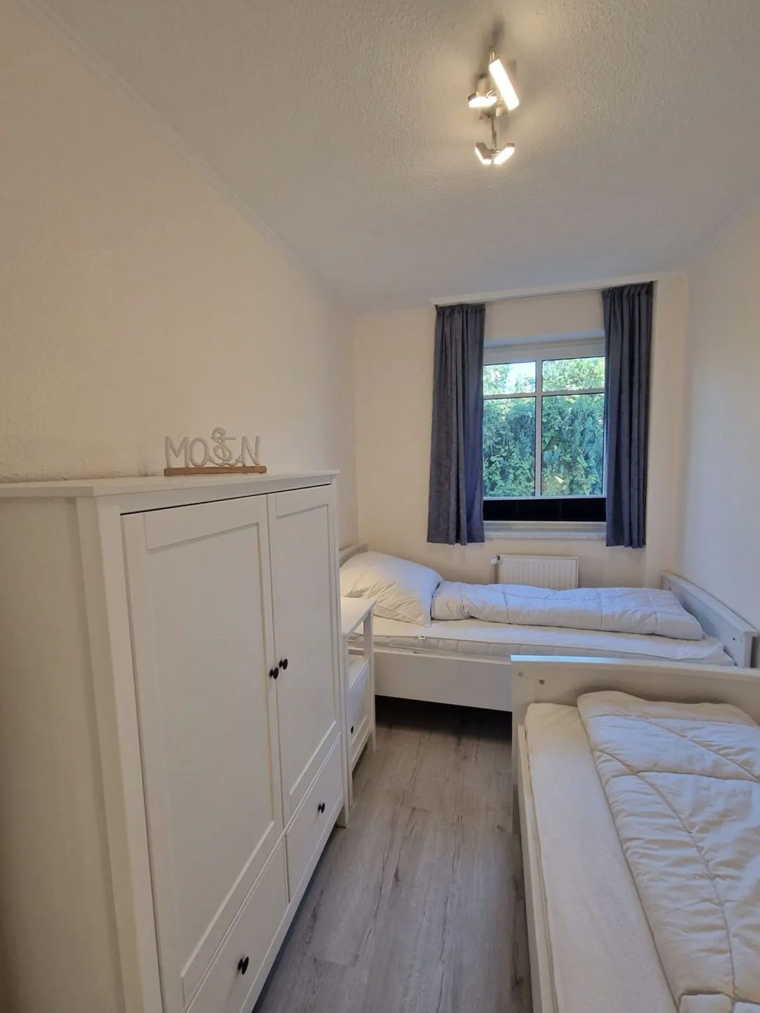 Zweites Schlafzimmer mit zwei Einzelbetten und weißem Kleiderschrank