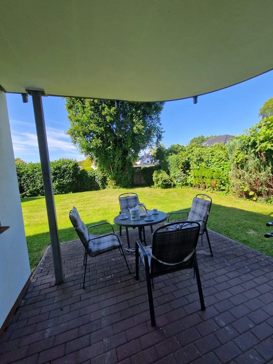 Terrasse unter dem Balkon mit Sitzgruppe und Rasenfläche